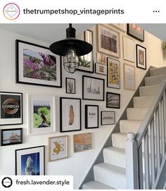 there is a staircase with many pictures on the wall and below it are stairs that lead up to the second floor