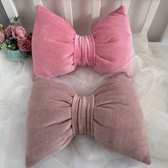 two pink velvet bow ties on top of a white crib with flowers in the background