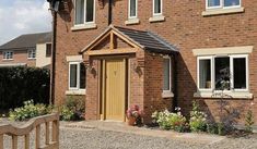 a brick house with a wooden bench in front of it and flowers on the side