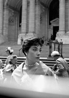 black and white photograph of woman in front of steps with other people sitting on benches