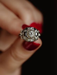 a woman's hand holding an antique diamond ring