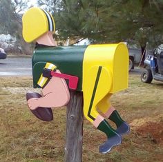 a mailbox shaped like a horse is painted green, yellow and pink in the shape of a man's head