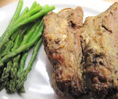 some meat and asparagus on a white plate