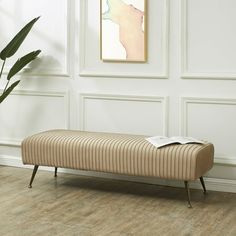 a bench sitting on top of a hard wood floor next to a plant in a room