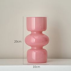 a pink vase sitting on top of a white shelf