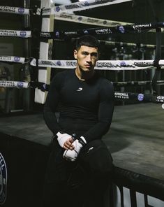 a man sitting on top of a bench in a boxing ring with gloves around his ankles