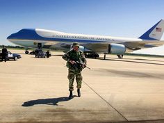 an air force officer standing in front of a plane on the tarmac with other vehicles nearby