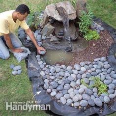 a man kneeling down next to a small pond filled with rocks and water flowing from it