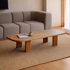 a living room with a couch, coffee table and television mounted on the wall above it