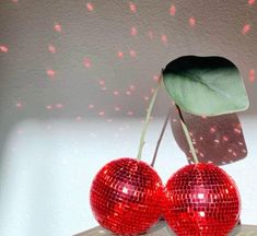 two shiny red balls sitting on top of a wooden table