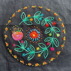 a colorful embroidered flower on a black cloth