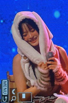 a woman in a bunny costume holding a microphone and smiling at someone on the stage