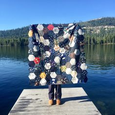 a person standing on a dock holding up a quilt