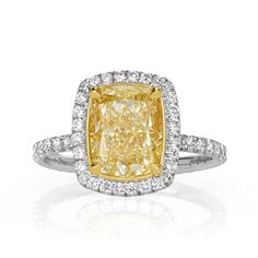 a yellow and white diamond ring with diamonds around it's sidestone, set in 18k white gold