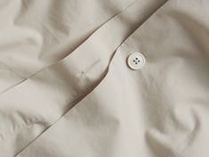 a button is on the side of a white shirt that's folded up and unbuttoned