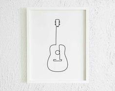 a black and white drawing of an acoustic guitar on a wall above a framed photograph