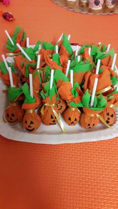 there are many pumpkins on the table with candy sticks in front of them and cupcakes to the side