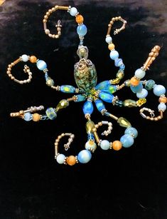 a blue and yellow necklace with beads on it's side, sitting on a black surface