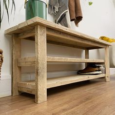 a wooden bench sitting on top of a hard wood floor next to a potted plant