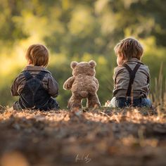 two little boys sitting on the ground with their teddy bears looking at something in the distance