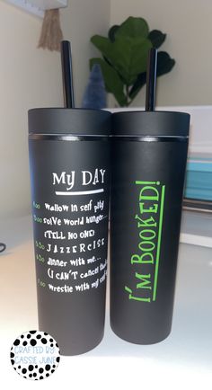 two black tumblers with green writing on them