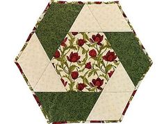 a green and white quilted hexagon with red flowers on the center is shown