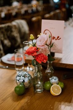 flowers and lemons are in vases on a table with a sign that says one