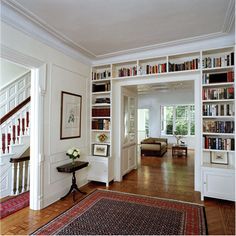 a living room filled with lots of books on top of a hard wood floor next to a doorway