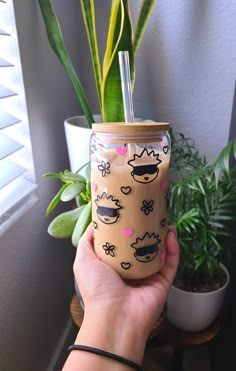 a person holding up a glass with some plants in it and a planter behind them