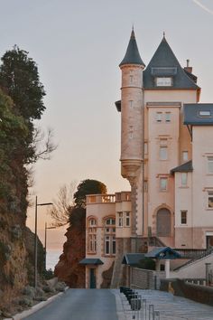 an old castle like building on the side of a road with stairs leading up to it