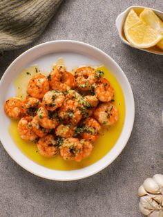 a white plate topped with shrimp next to garlic and lemon