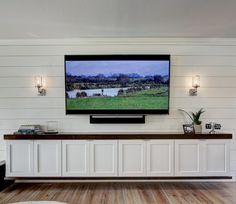 a flat screen tv mounted to the side of a wall next to a wooden floor