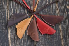 six different colored leather spoons in a circle on top of a wooden table,