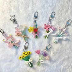 six flower key chains are arranged in a circle on a white surface with tiny flowers