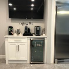 a coffee bar with stainless steel appliances and flat screen tv mounted above the refrigerator freezer