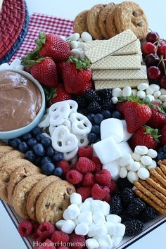 a platter filled with crackers, berries, marshmallows and pretzels