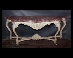 an antique console table with red marble top