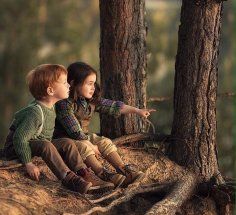 two children are sitting on a rock in the woods