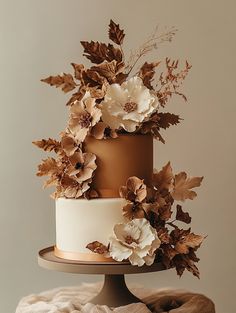 a three tiered cake decorated with flowers and leaves