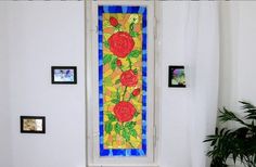 a stained glass window with red roses on it in a white room next to a potted plant