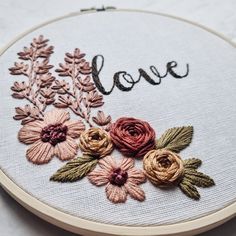 a close up of a embroidery on a hoop with flowers and the word love written in it