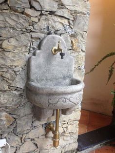 a stone wall with a sink and faucet attached to it, next to a potted plant