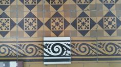 some tiles are on the wall and one has a black and white design in it