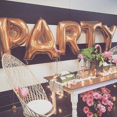 some balloons that are on the wall near chairs and a table with flowers in it