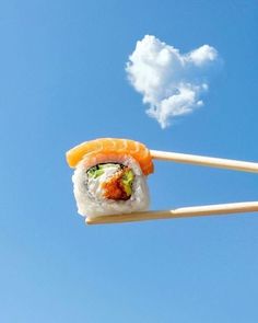 two chopsticks with sushi on them are flying in the air against a blue sky