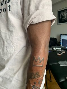 a man with a tattoo on his arm standing in front of a desk and computer