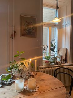 a wooden table topped with candles next to a window