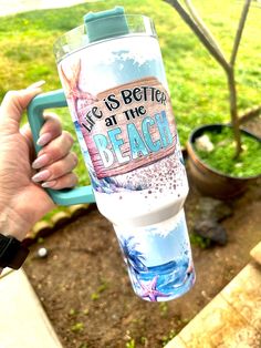 someone holding up a water bottle with the words life is better at the beach on it