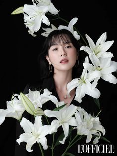 a woman is surrounded by white flowers in front of a black background with the caption to officiel