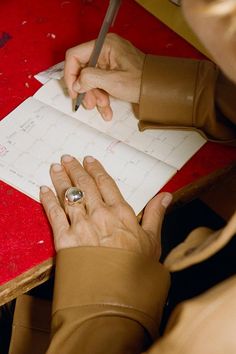 a woman is writing on a piece of paper while holding a pen in her hand